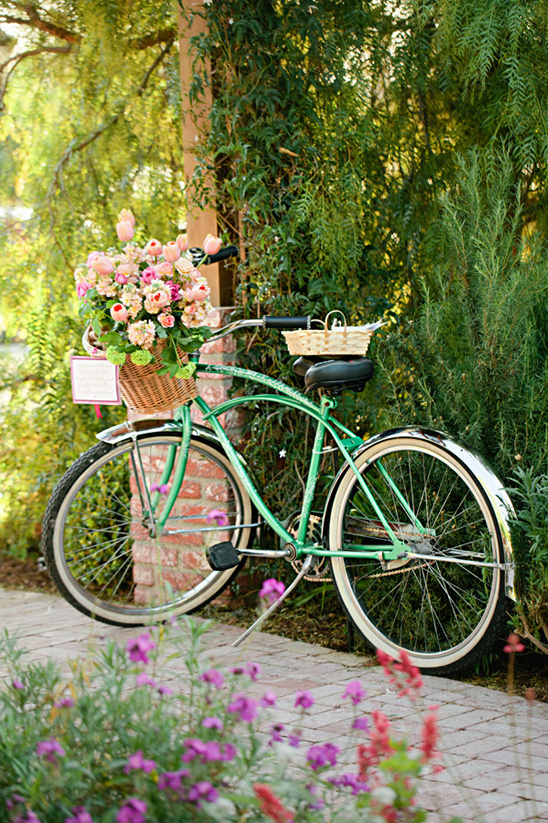 Green bicycle with flowers in basket