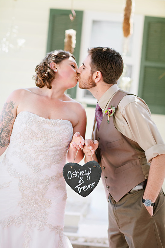 Ashley & Trevor kissing, holding heart wedding sign