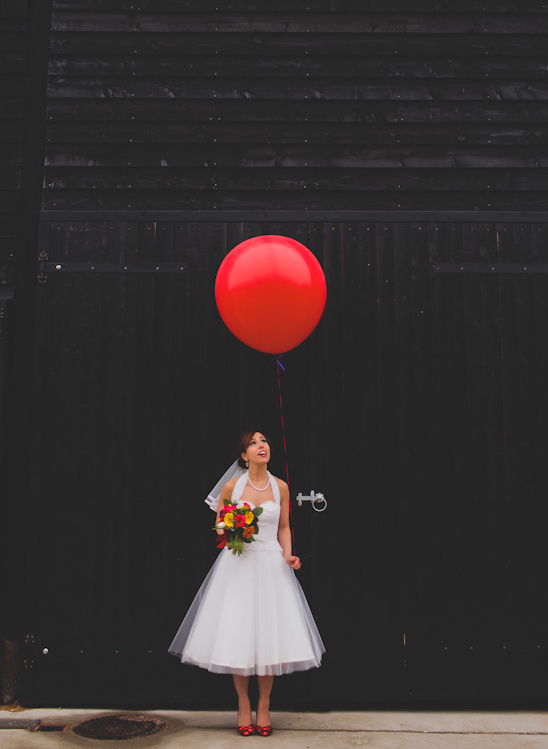 Bride in a white dress holding a bouquet with a red balloon