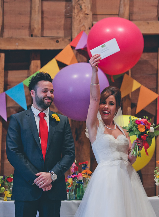Happy bride holding gift at wedding with groom smiling beside