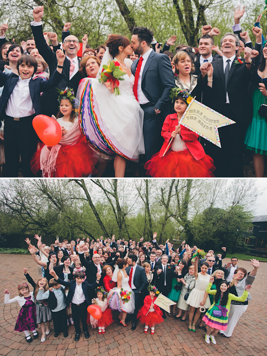 Joyful wedding group photo with bride and groom kissing