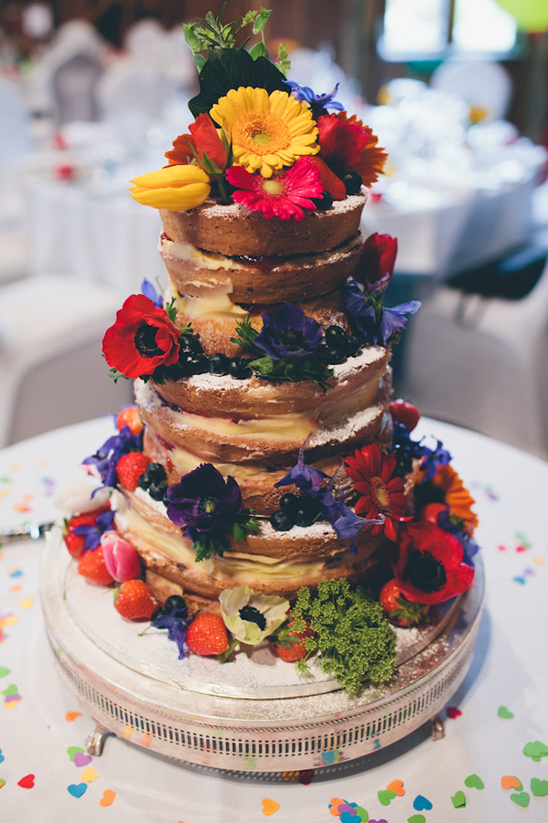 A beautiful three-tiered cake decorated with fresh flowers and berries