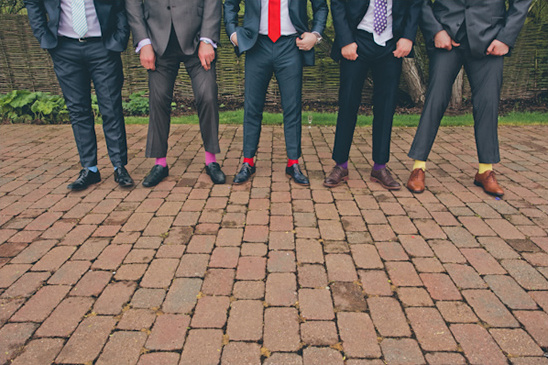 Men in suits with colorful socks posing on a brick walkway