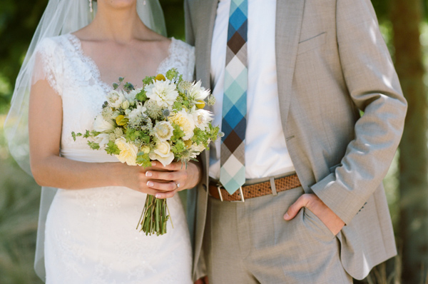 Bride and groom pose together with bouquet, wedding day