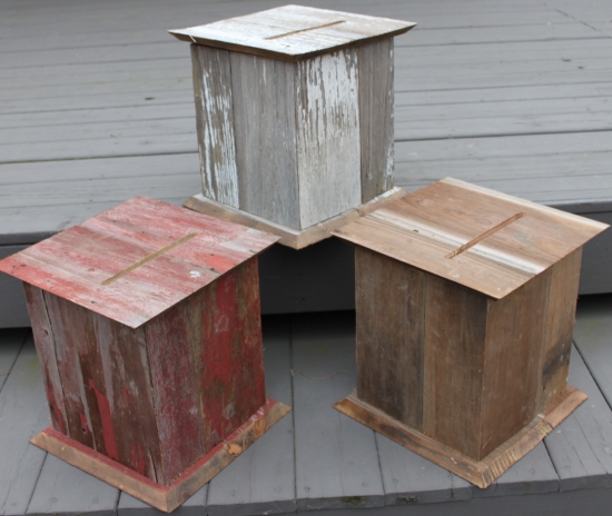 Three weathered wooden donation boxes on a wooden deck