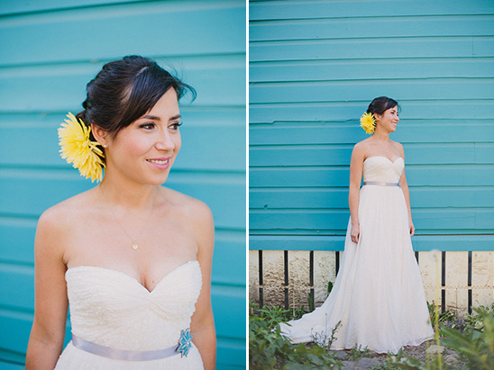 Elegant bride smiles, wearing a white dress with a yellow flower in her hair