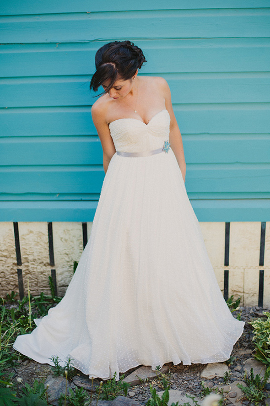 Elegant bride in a white wedding dress by a blue wall