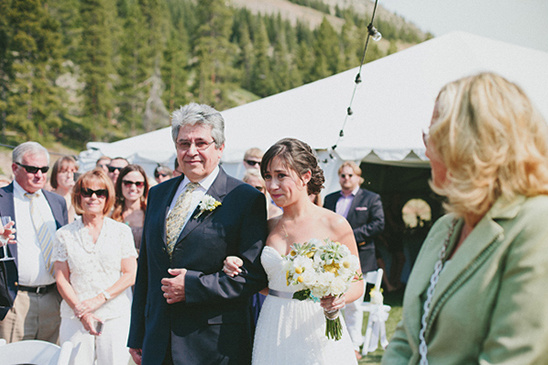 Bride walking down the aisle with her father at an outdoor wedding