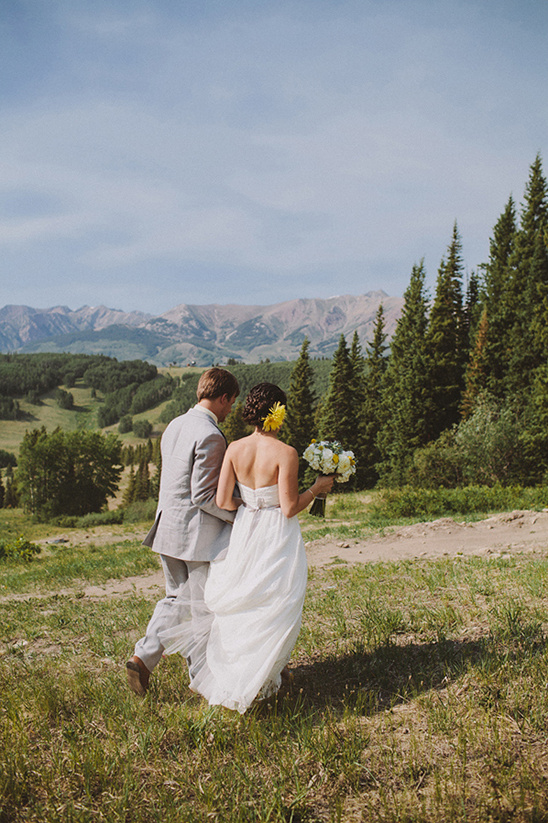 Bride and groom walking towards mountains on wedding day