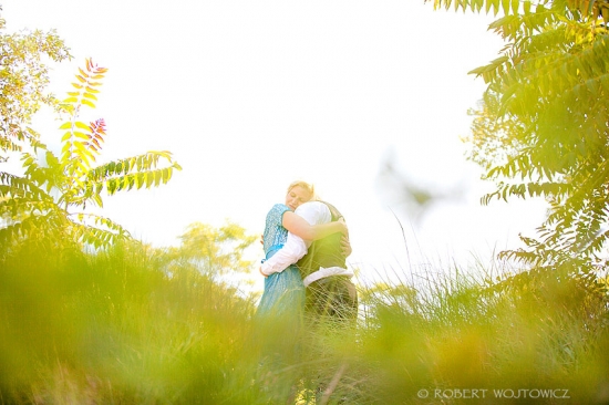 Couple embracing in a sunlit field of green grass and foliage