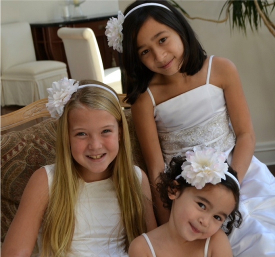 Three smiling girls with flower headbands in white dresses