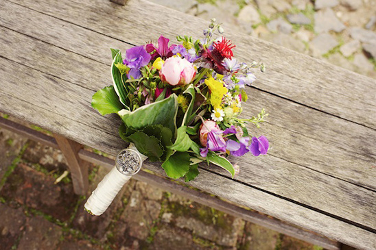 A beautiful bouquet of colorful flowers resting on a wooden bench
