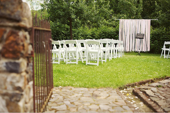 Outdoor wedding ceremony setup with white chairs and decorations