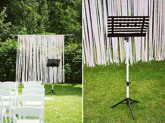 Wedding ceremony setup with music stand and ribbon backdrop
