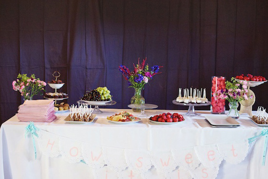 A beautifully decorated dessert table with various sweet treats and fruits