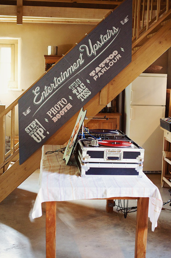 DJ setup with a sign promoting upstairs entertainment