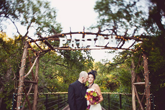 A wedding couple under an arch of lights