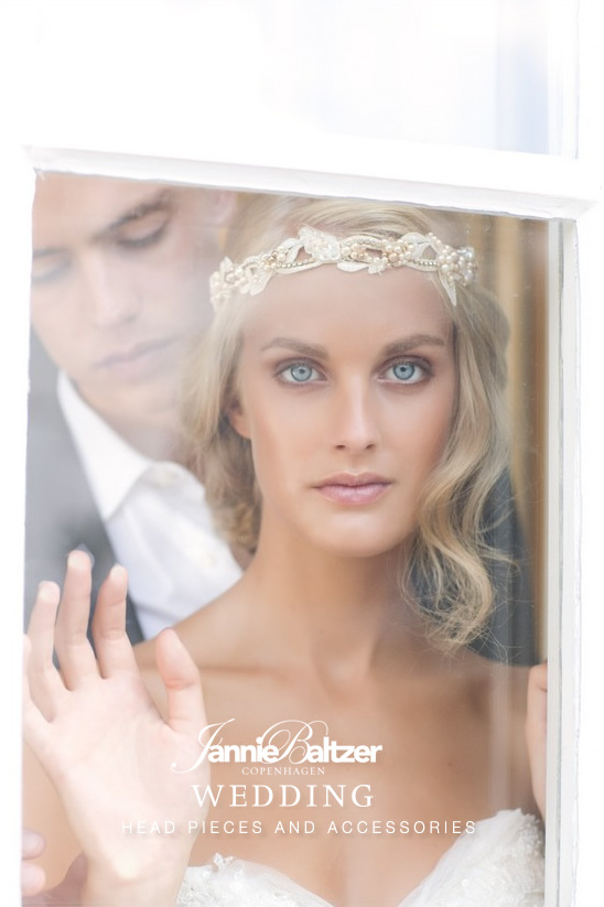 Bride and groom behind window with bridal headpiece looking at you