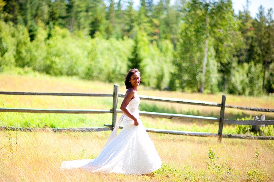 Smiling bride in a white dress walking through a field on her wedding day