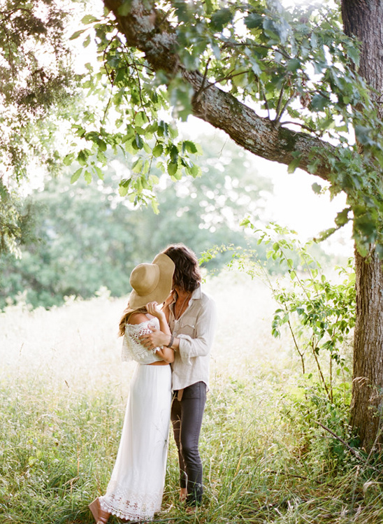 Couple embracing under a tree in a sunlit field for a moment