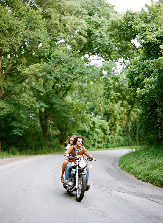 Couple riding a vintage motorcycle on a winding road, outdoors