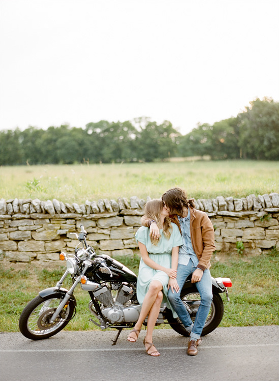 Couple kissing next to a motorcycle, romantic outdoor setting