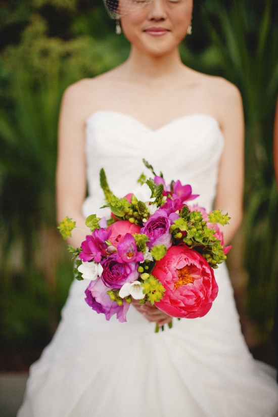 Bride holding colorful bouquet, wedding dress, floral arrangement