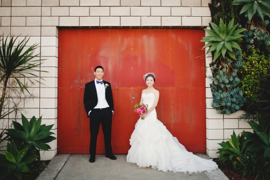 Asian couple on their wedding day posing in front of red door