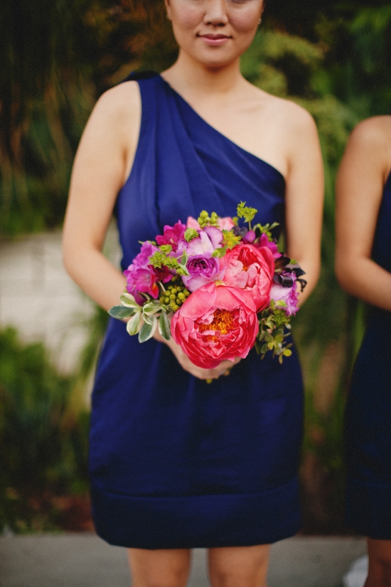 Bridesmaid in a blue dress holding a vibrant colorful bouquet of flowers