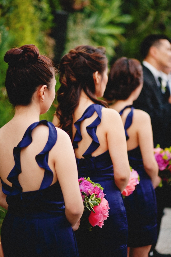 Bridesmaids in elegant blue dresses hold bouquets at a wedding