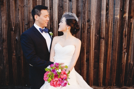 Happy couple embracing on wedding day near wooden background