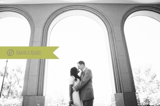A loving couple embraces beneath elegant archways in black and white
