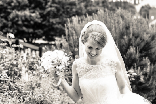 Happy bride smiling holding flowers at outdoor wedding
