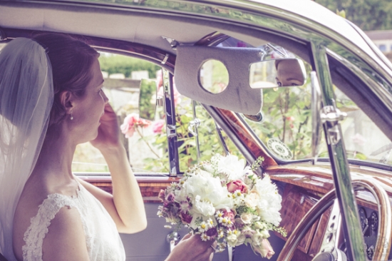 Bride in car adjusting veil, wedding bouquet in hand