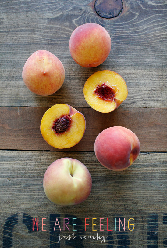 Fresh peaches on a wooden surface, with the words just peachy