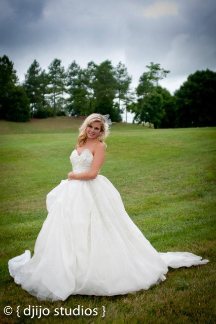 Happy bride in a white wedding dress smiling on a field of grass