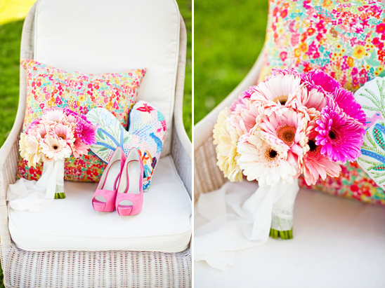 Pink gerbera daisies, shoes, and pillow on a white chair for a wedding