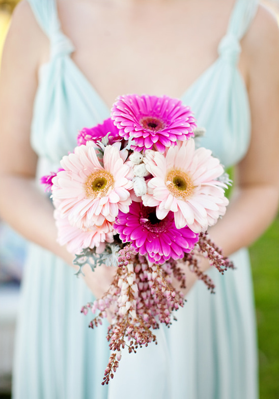 Woman in blue dress holding a bouquet of pink gerbera daisies