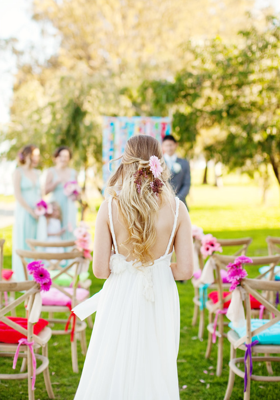 Bride in white dress walking towards ceremony outdoors