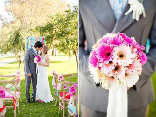 Wedding kiss with a bouquet of pink gerbera daisies and ceremony setting