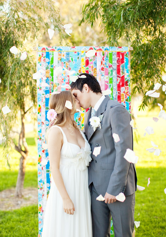 Bride and groom kissing as flower petals fall during wedding