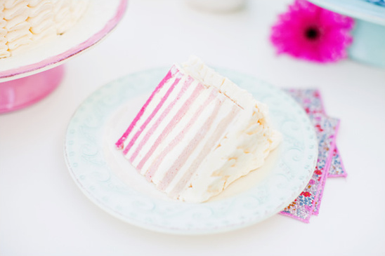 Slice of a layered cake with pink stripes on a decorative plate