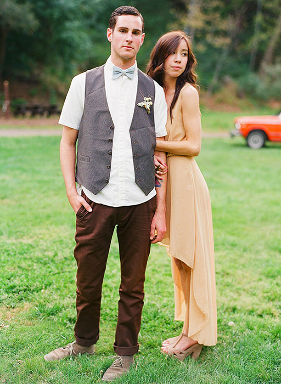 A stylish couple stands together, outdoor wedding portraits on green grass