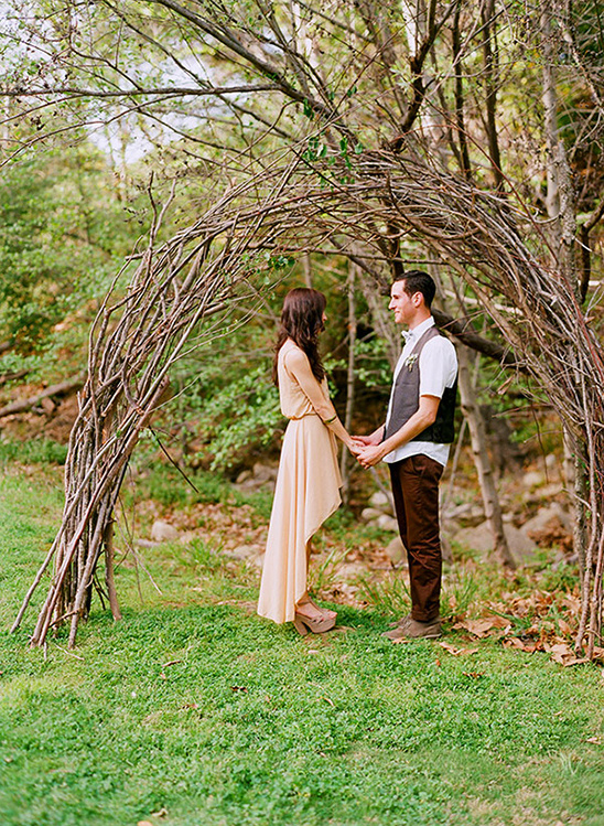 Couple holding hands under rustic arch in a forest setting