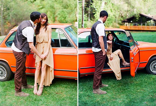 Romantic couple poses by orange vintage car for engagement photos