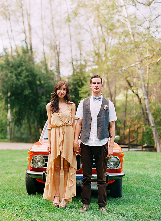 Couple holding hands next to a vintage car on a sunny day