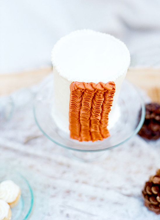 A beautifully decorated white cake with textured orange frosting