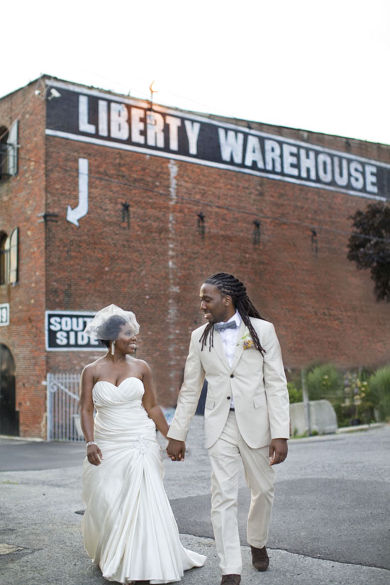 Newlyweds walk hand-in-hand in front of Liberty Warehouse