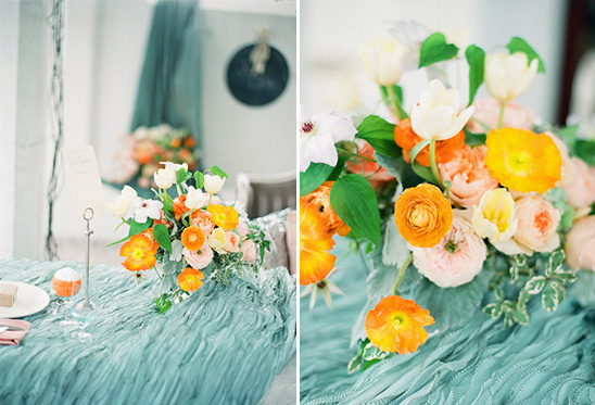 Vibrant floral centerpiece with orange and white flowers on teal linen