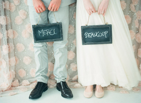 Couple holding chalkboards with Merci and Beaucoup for their wedding